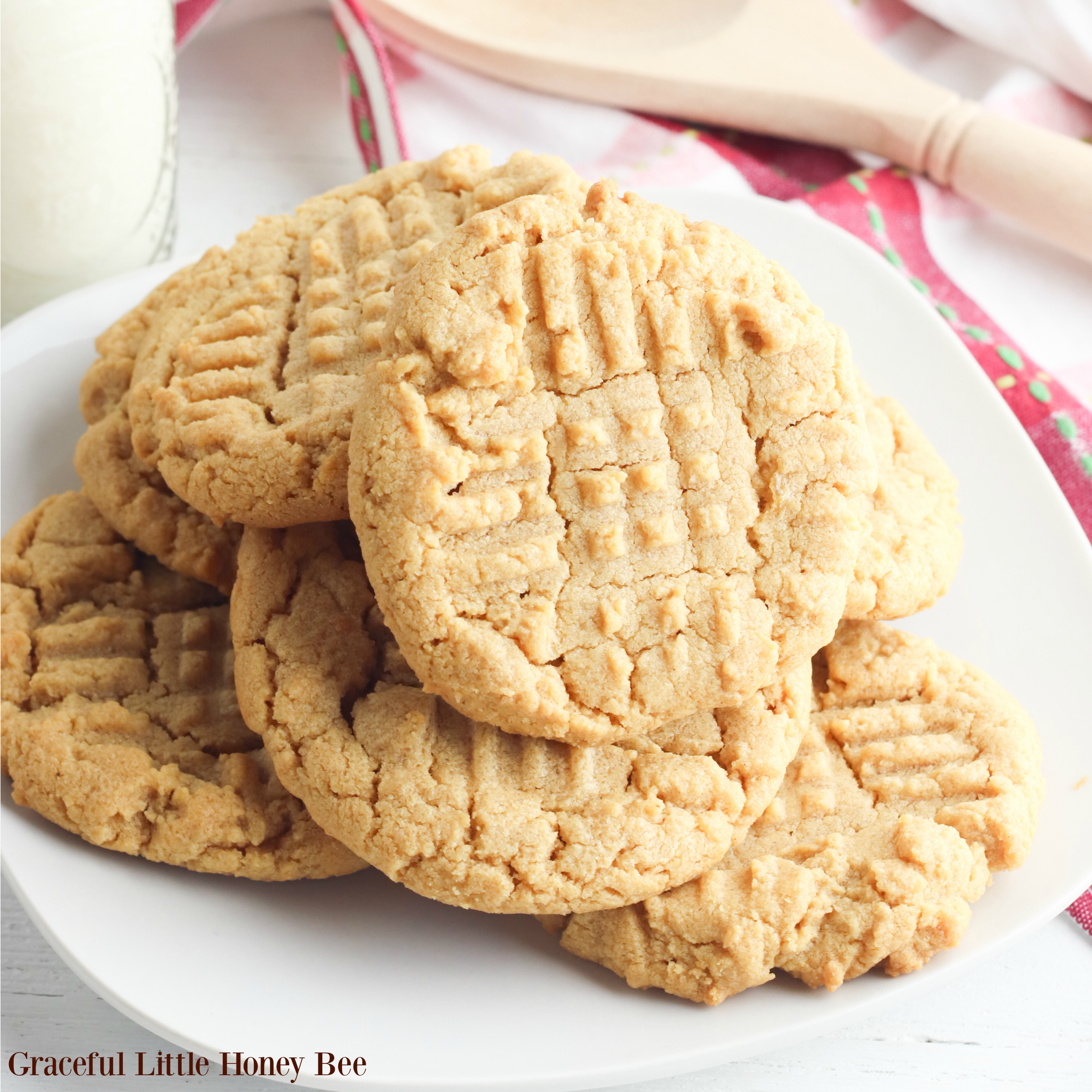 Peanut Butter Cookies piled on a white plate with a red towel in the background.