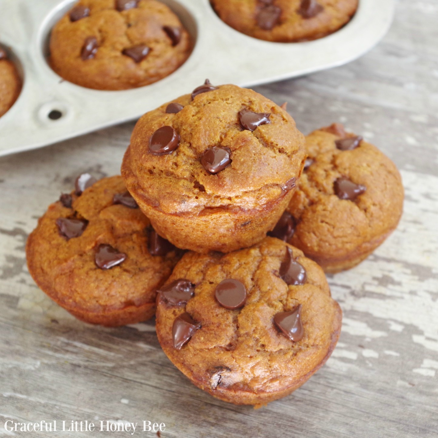 Stacked Pumpkin Chocolate Chip Muffins on a cutting board.