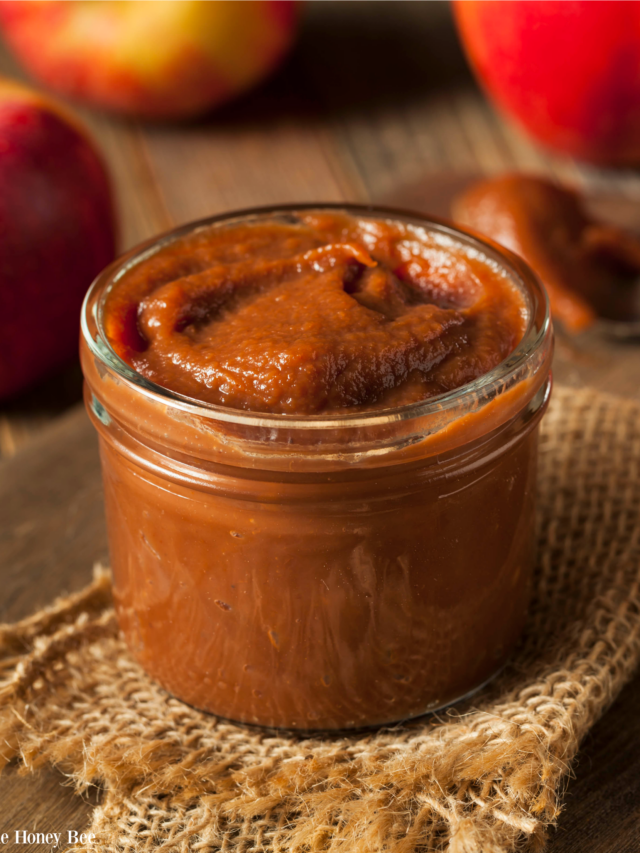 Finished apple butter in a mason jar sitting on a piece of burlap with a wood background.