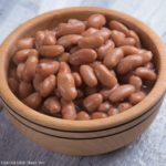 A brown bowl of cooked pinto beans.