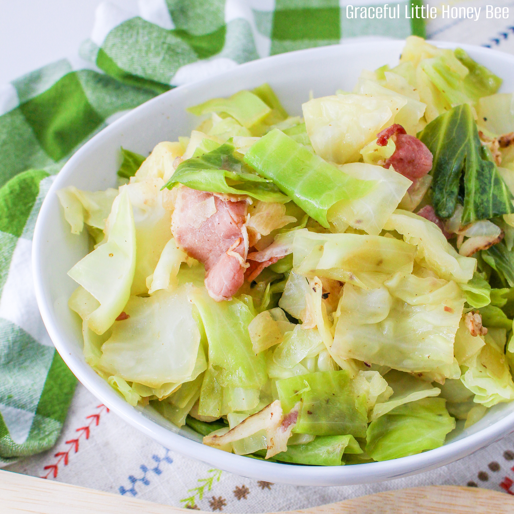 Close up view of fried cabbage with bacon in a white bowl.