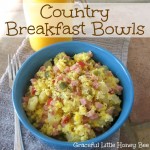 Diced ham, potatoes, peppers, and scrambled eggs in a blue bowl. With a glass of orange jucie in the background.