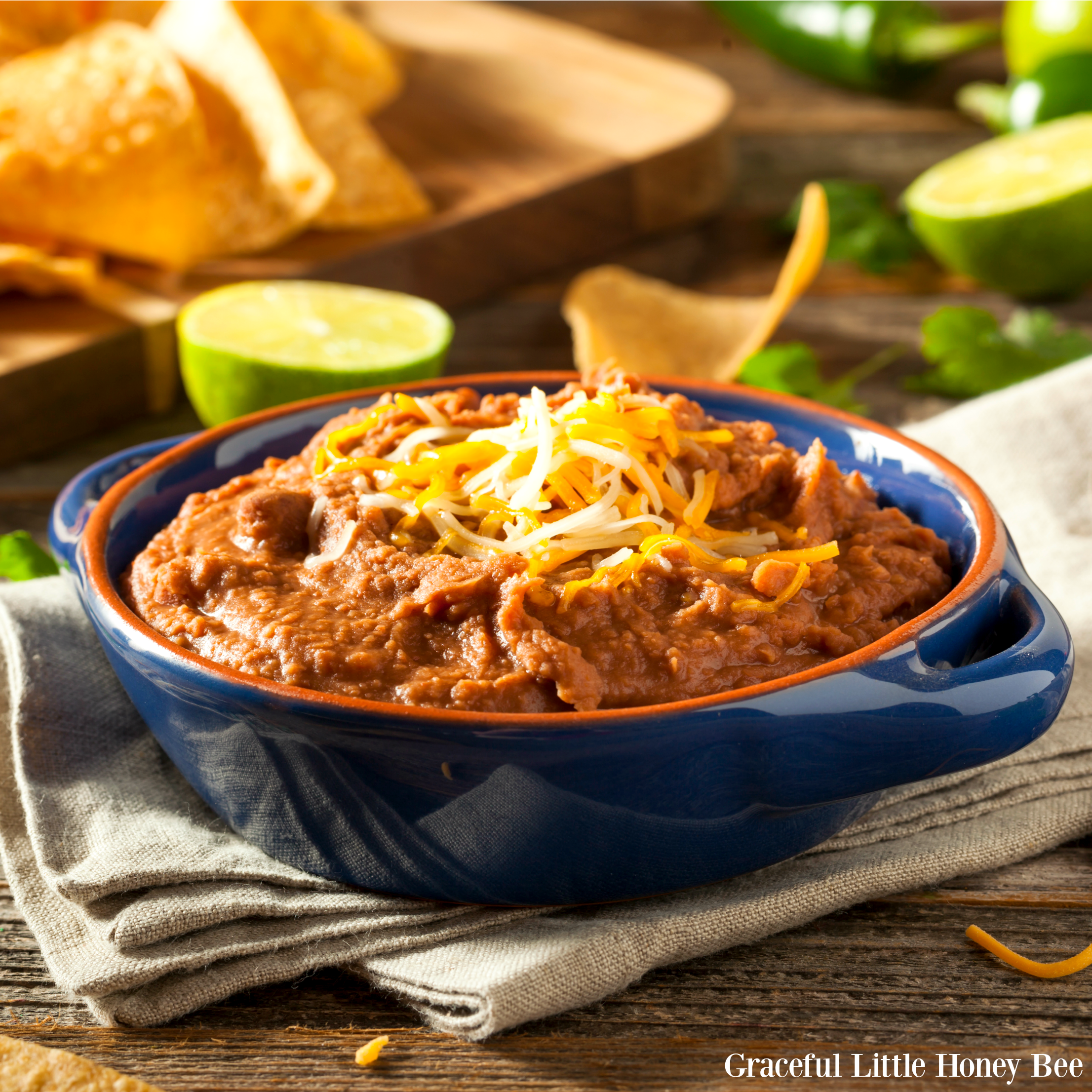 Refried beans in a blue bowl with shredded cheese on top.