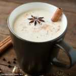 Chai tea in a brown mug with a stick of cinnamon.