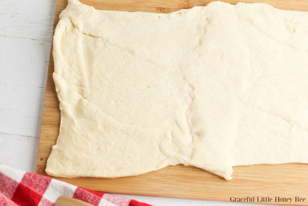 Crescent roll dough lying flat on a cutting board.