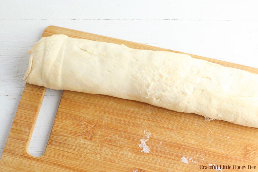 Filled crescent roll dough rolled into stromboli shape, before going into the oven.