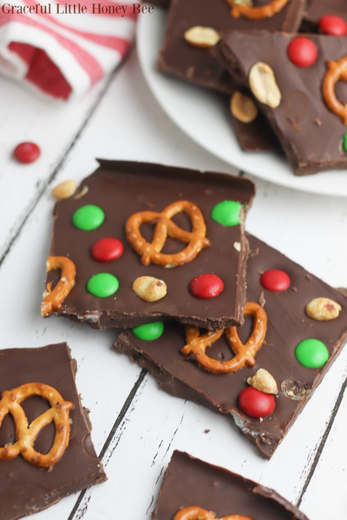 Chocolate christmas bark on a baking sheet with pretzels, peanuts and candies.