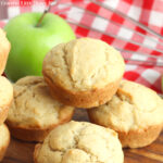 Applesauce muffins sitting on a pile with green apples in the background.