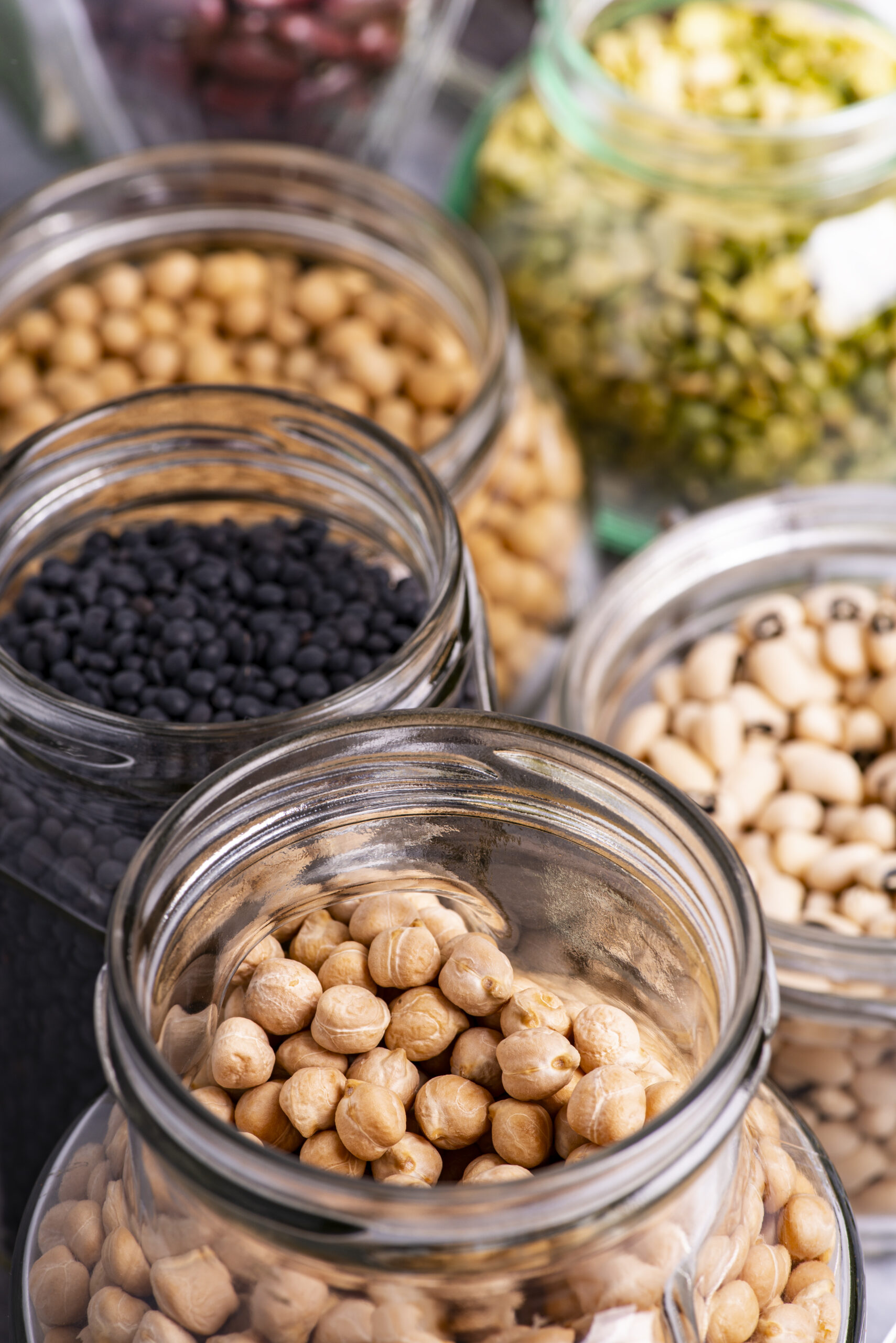 variety of dried legumes in glass jars. selective focus on the jar in the foreground with chickpeas