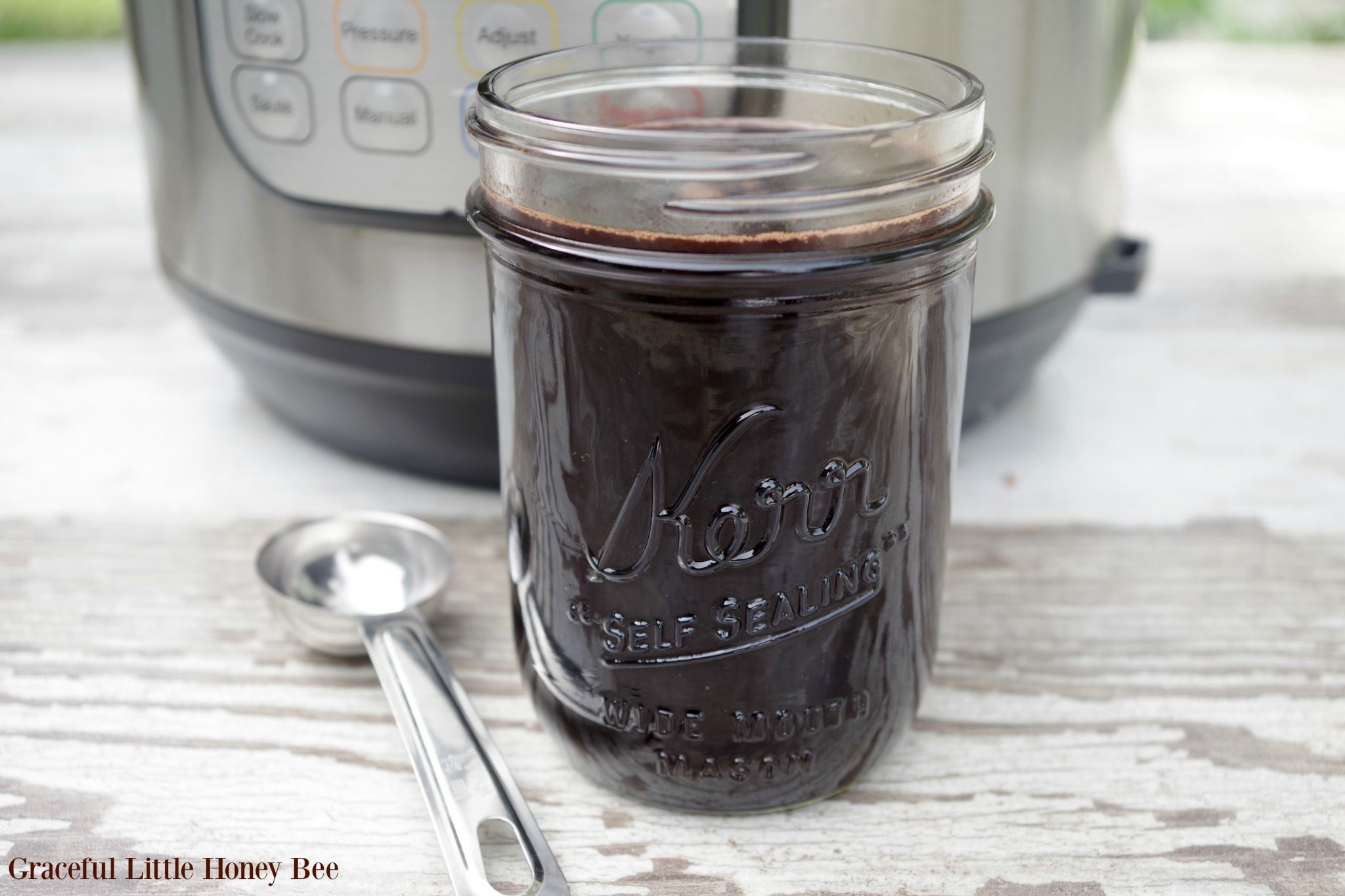 Elderberry syrup in a mason jar with an Instant Pot in the background.