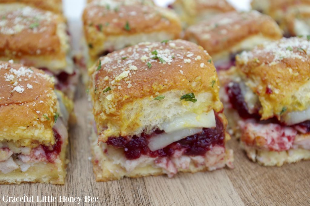 Turkey Cranberry Sliders sitting on a wooden cutting board.