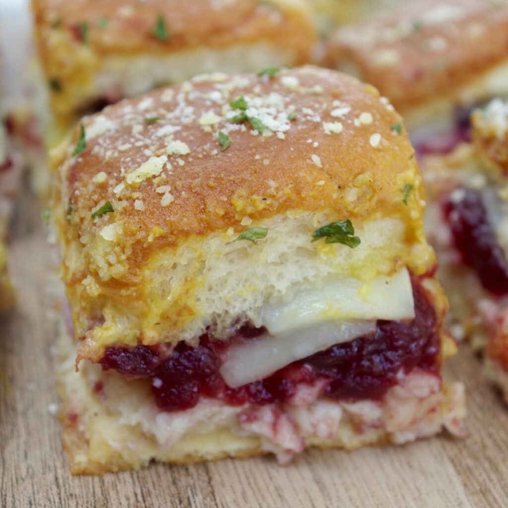 Turkey Cranberry Sliders sitting on a wooden cutting board.