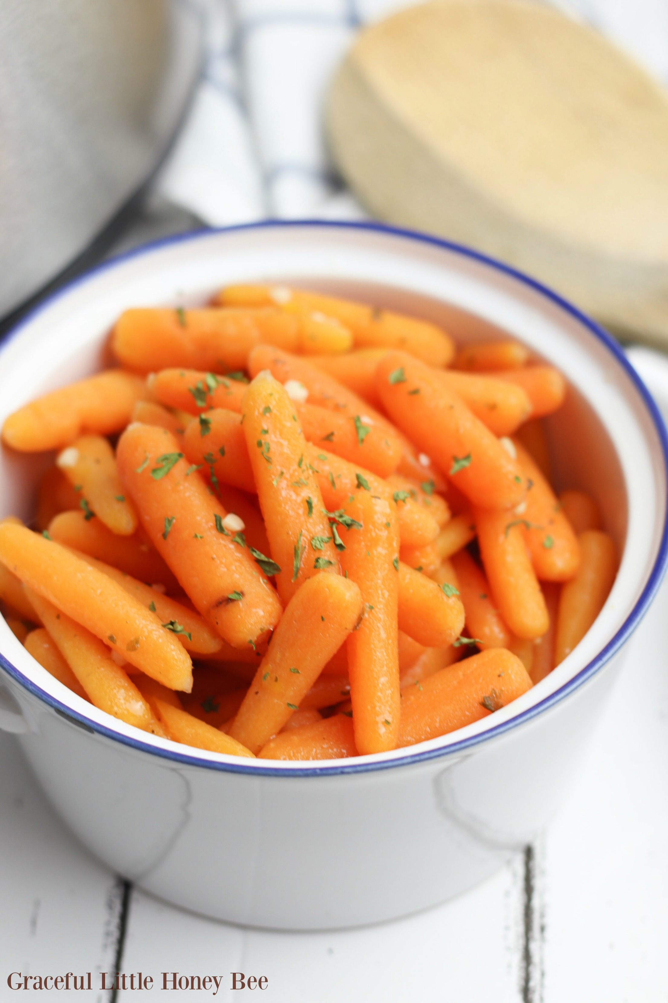 Cooked baby carrots on a white bowl.