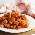 Oven-roasted sweet potatoes and bacon on a white plate.