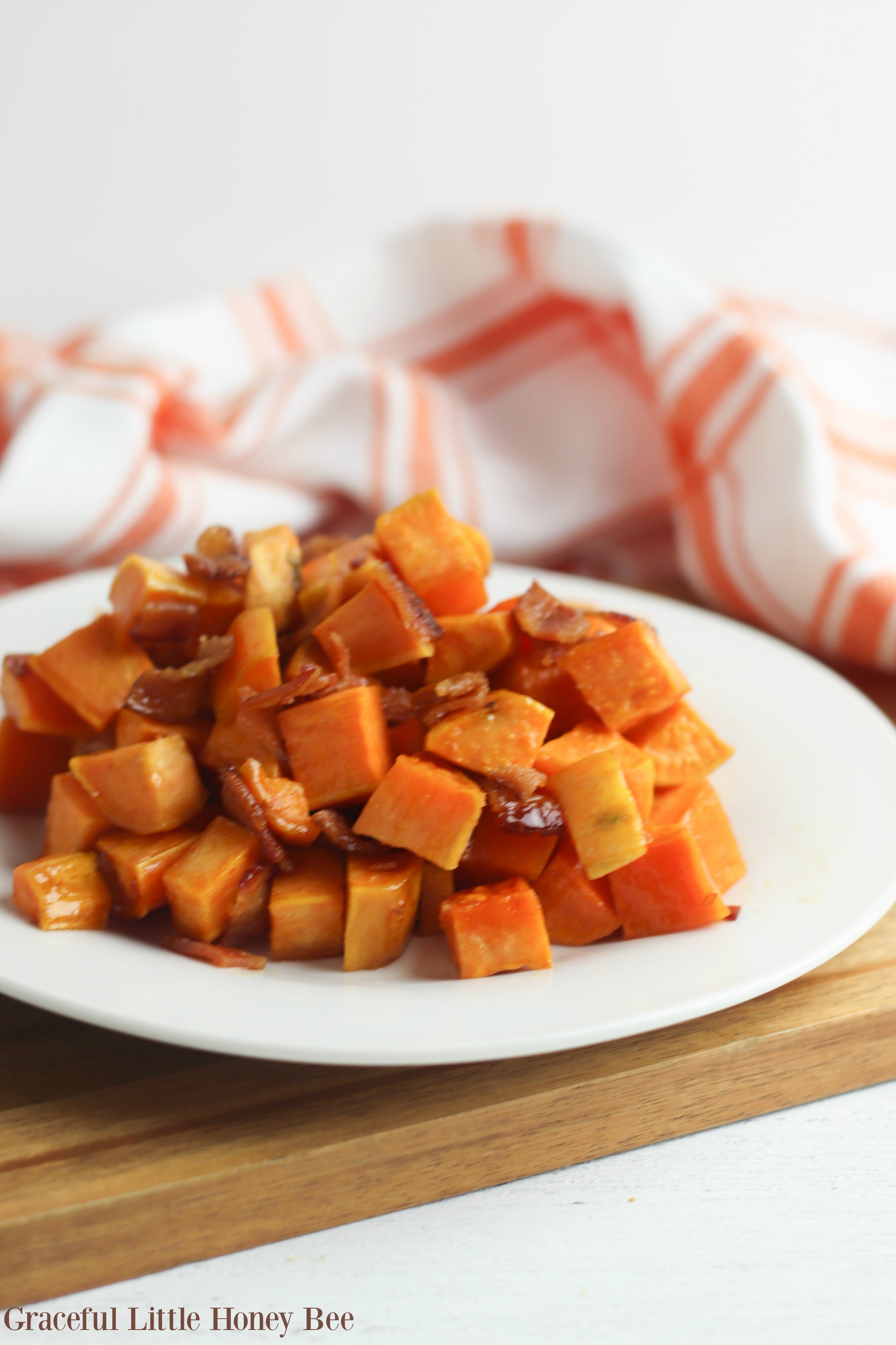 Oven-roasted sweet potatoes and bacon on a white plate.