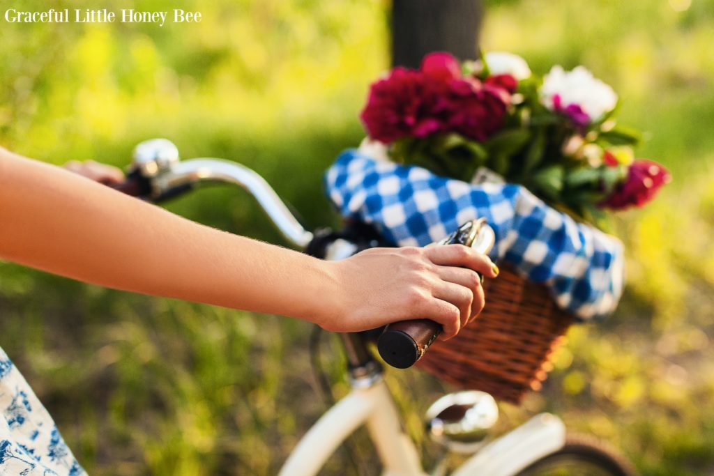 A basket full of colorful flowers on the front of a white bicycle.