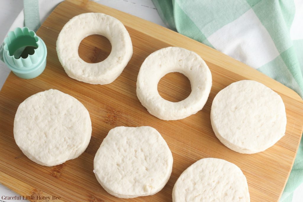 Biscuit dough on a cutting board with holes cut out of the middle.