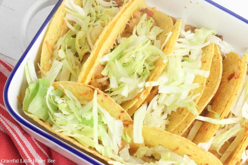 Finished tacos topped with lettuce in baking dish.