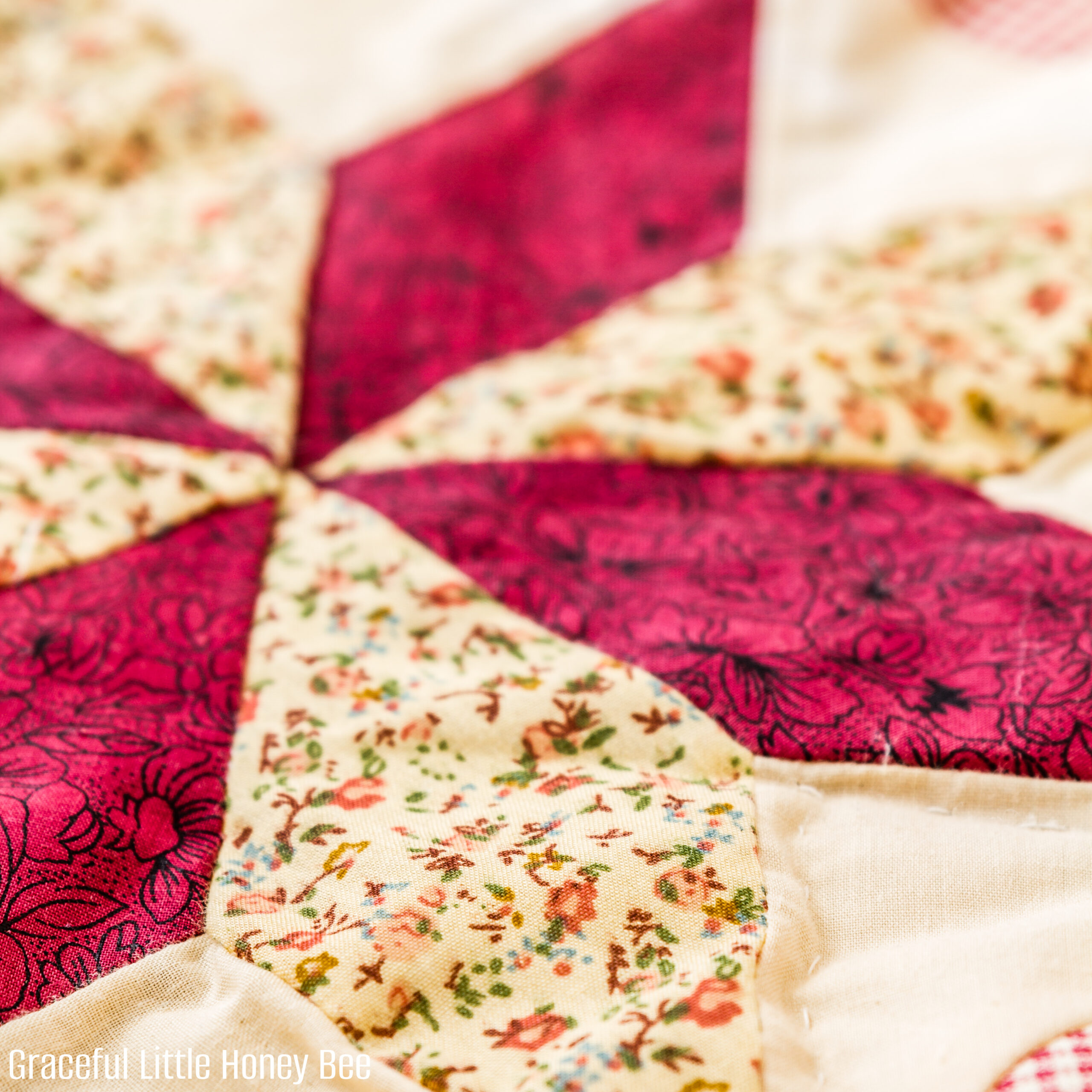 A close up of a pink and cream quilt star.