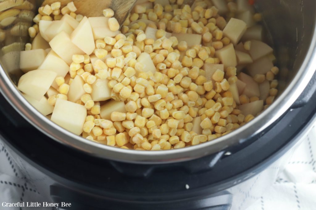 Carrots, onions, diced potatoes and corn in the Instant Pot before cooking.