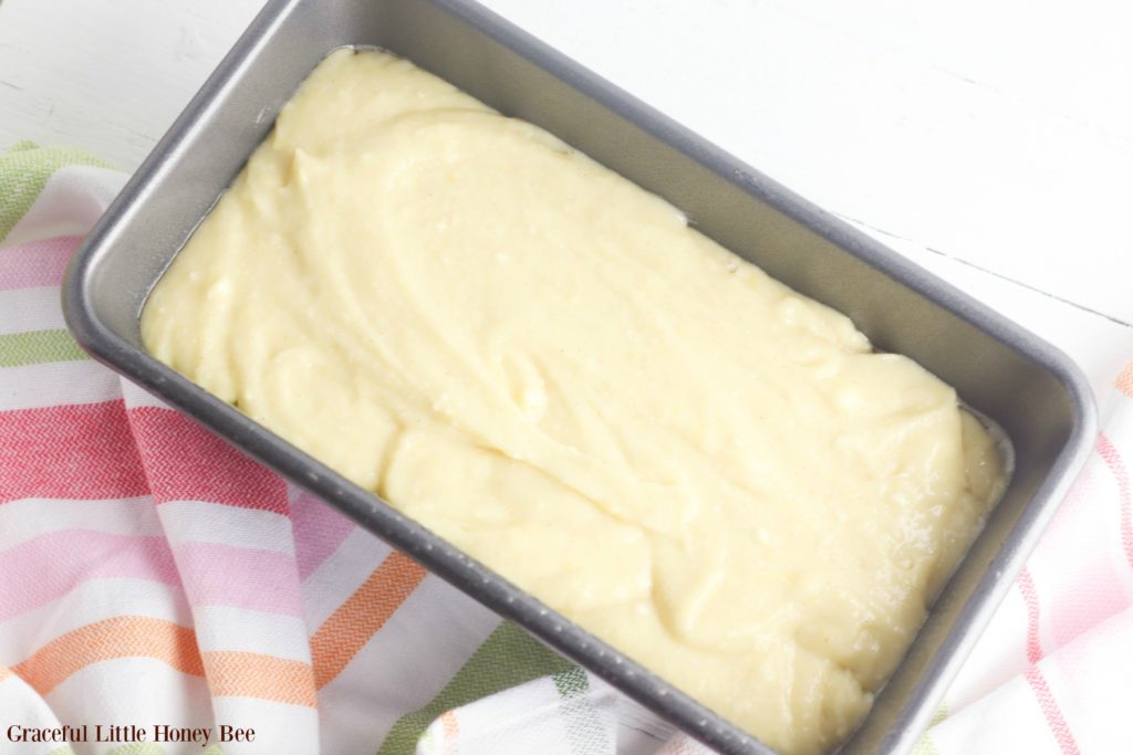 Raw pound cake batter in cake pan sitting a tea towel.