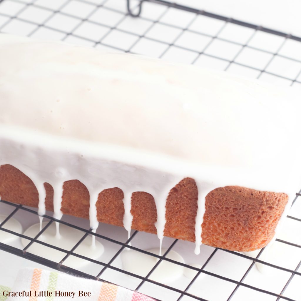 Finished pound cake drizzled with glaze on a cooling rack.