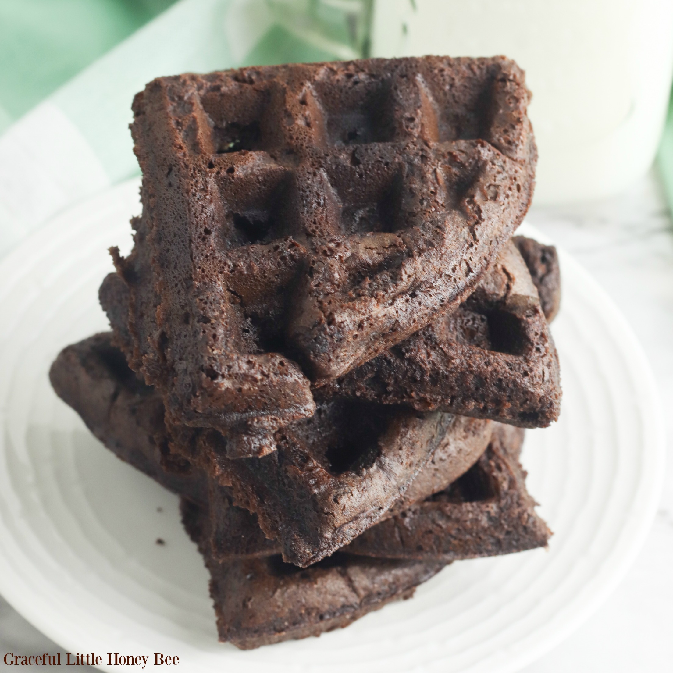 Finished brownie waffles stacked on a white plate.