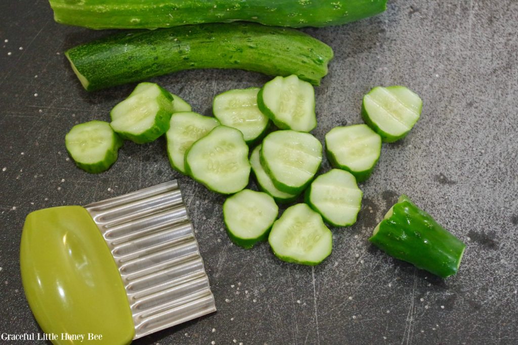 Crinkle cut slices of cucumbers lying on a cutting board.