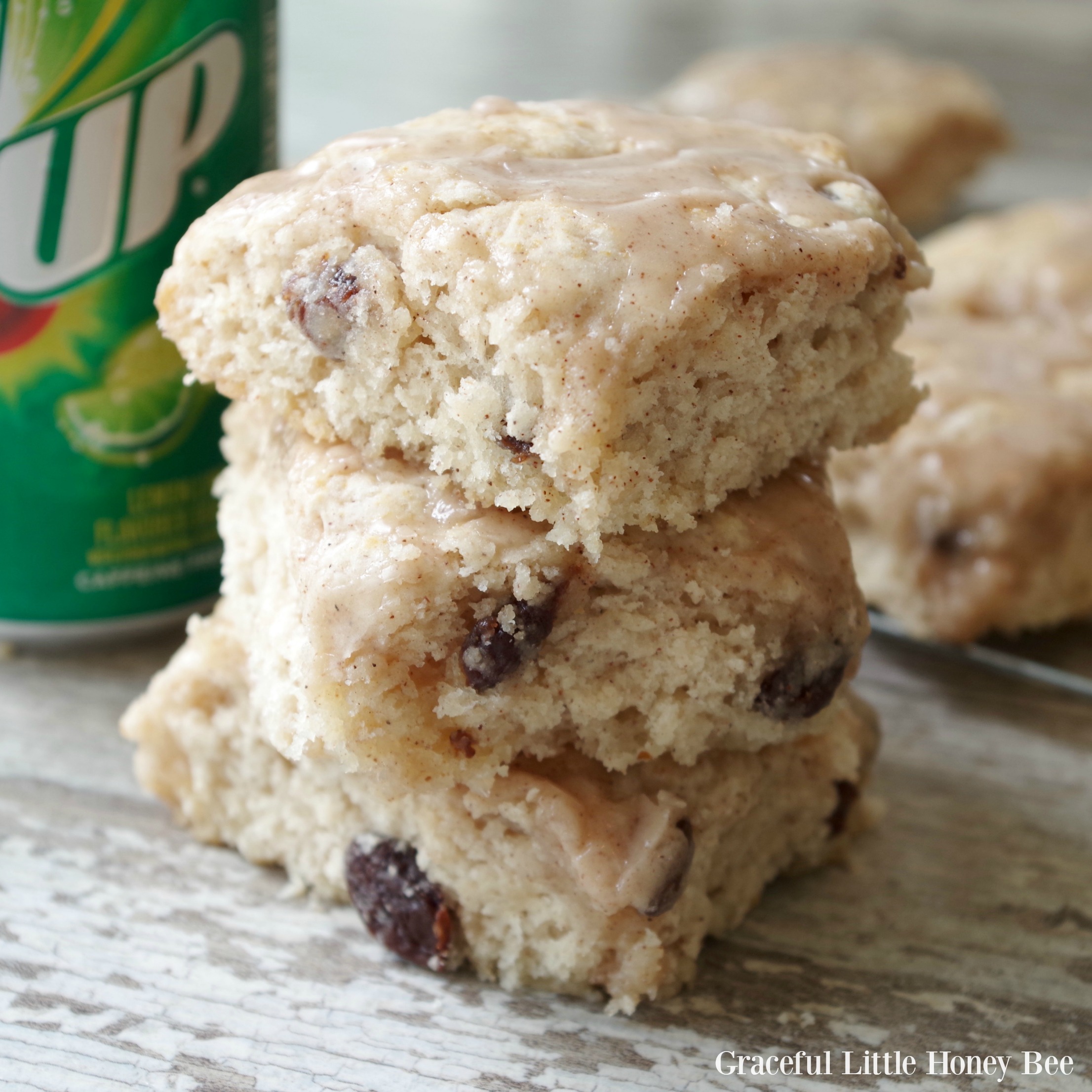 Three cinnamon raisin biscuits stacked on a wooden board with a 7-Up can in the background.