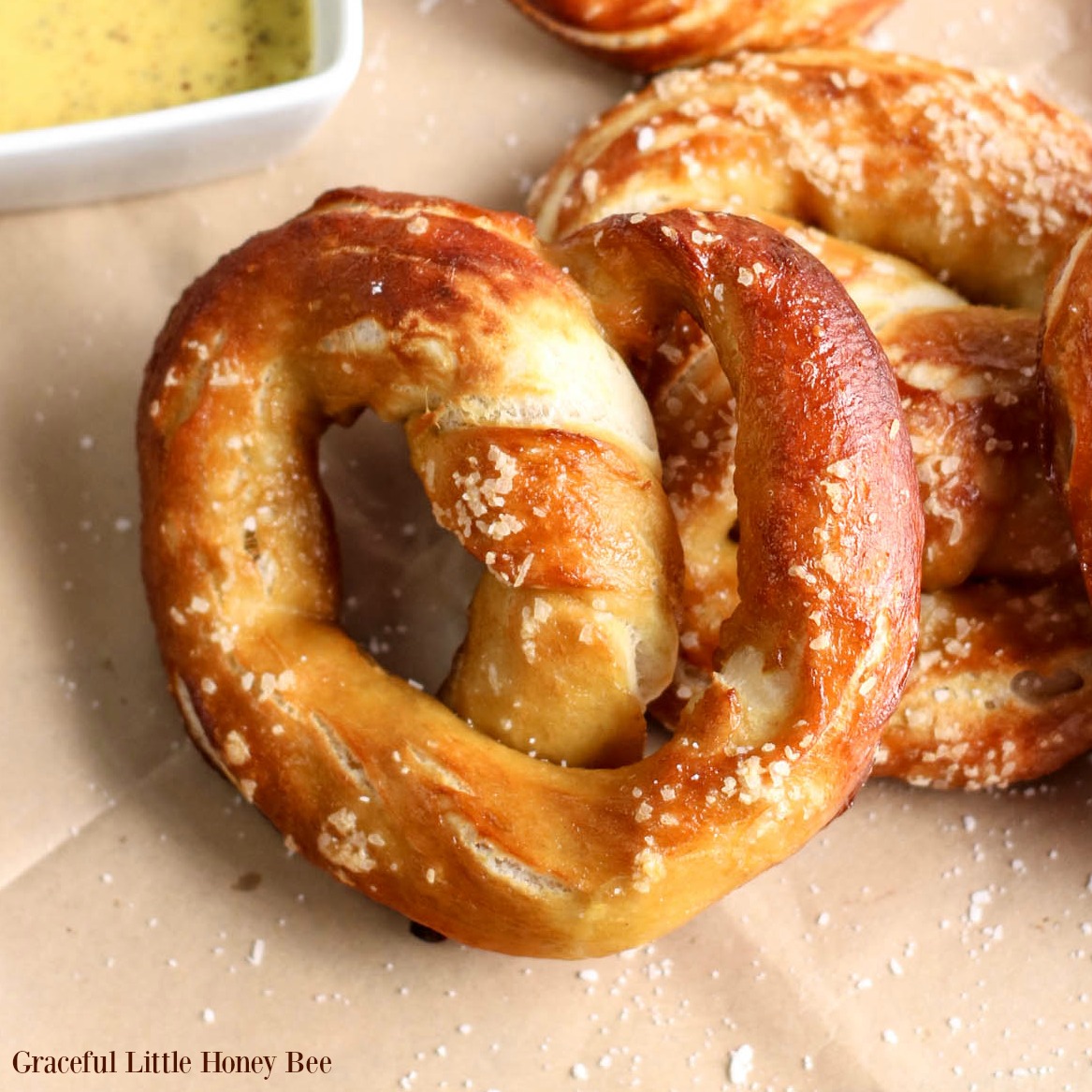 Finished baked pretzels with mustard dipping sauce in the background.