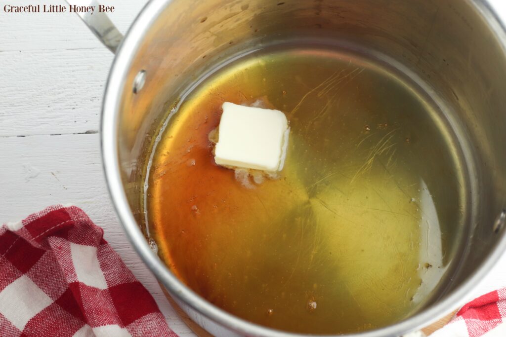 Apple cider and butter in a saucepan.