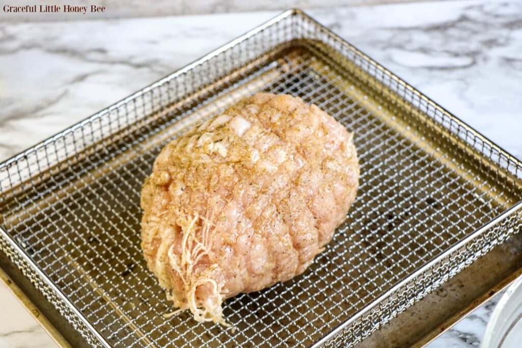 Raw turkey breast sitting in air fryer basket.