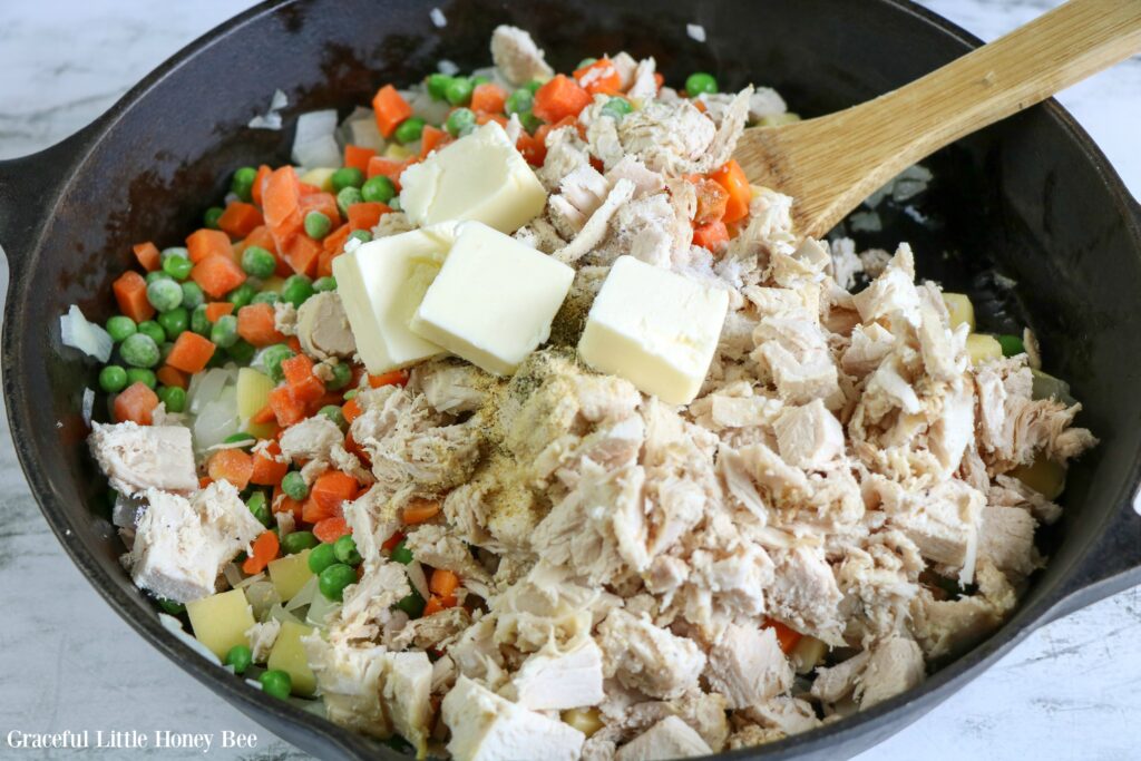 Mixed vegetables, cooked turkey and butter in a cast iron skillet.