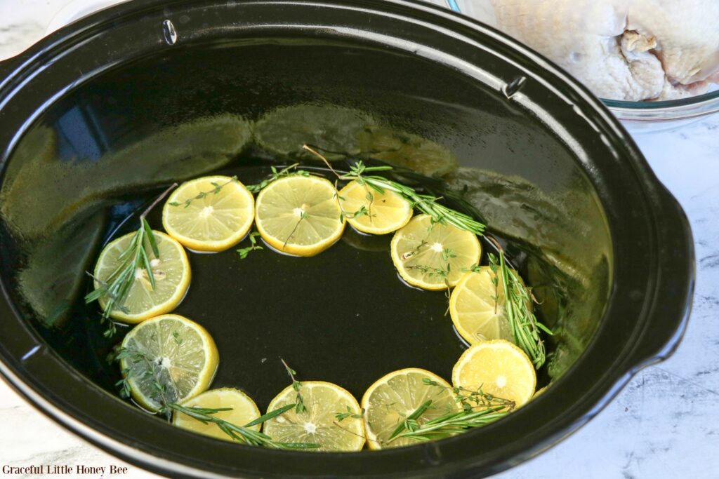 Rosemary and Lemon lining the bottom of the slow cooker.