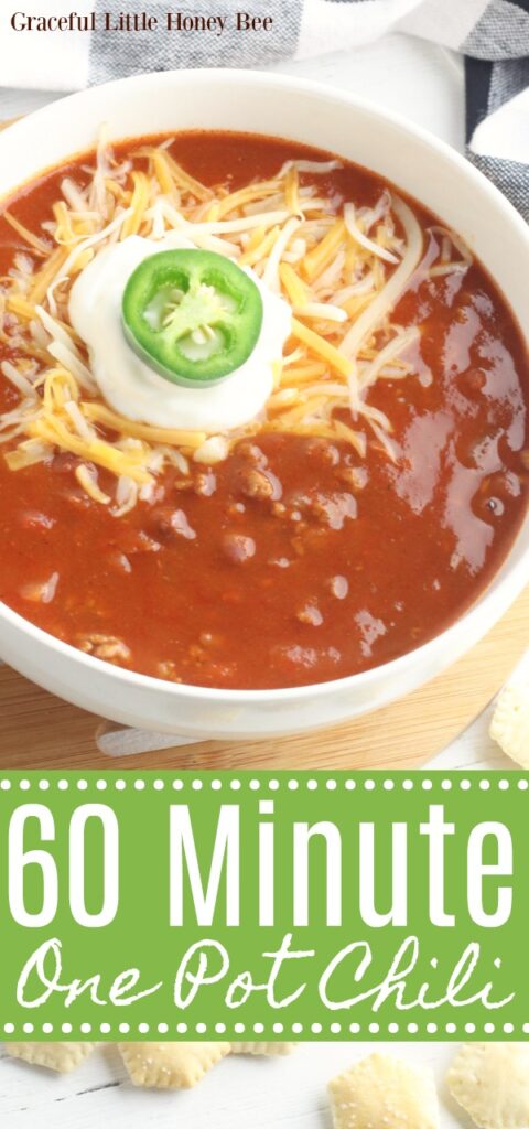 V8 Chili in a white bowl garnished with shredded cheese, sour cream and jalapeno.