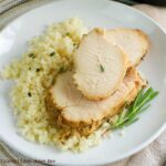 Tender, juicy turkey breast served on a whilte plate over rice garnished with fresh Rosemary.