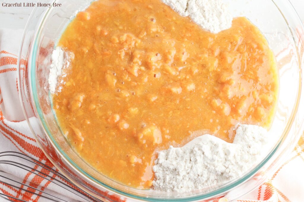 Wet ingredients dumped over dry ingredeints in a mixing bowl.