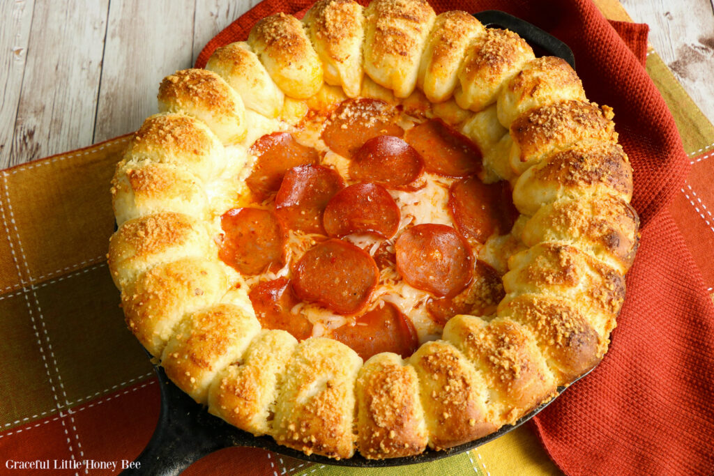 Cheesy Pizze Dip topped with pepperoni with a ring of garlic bread around it in a cast iron skillet.