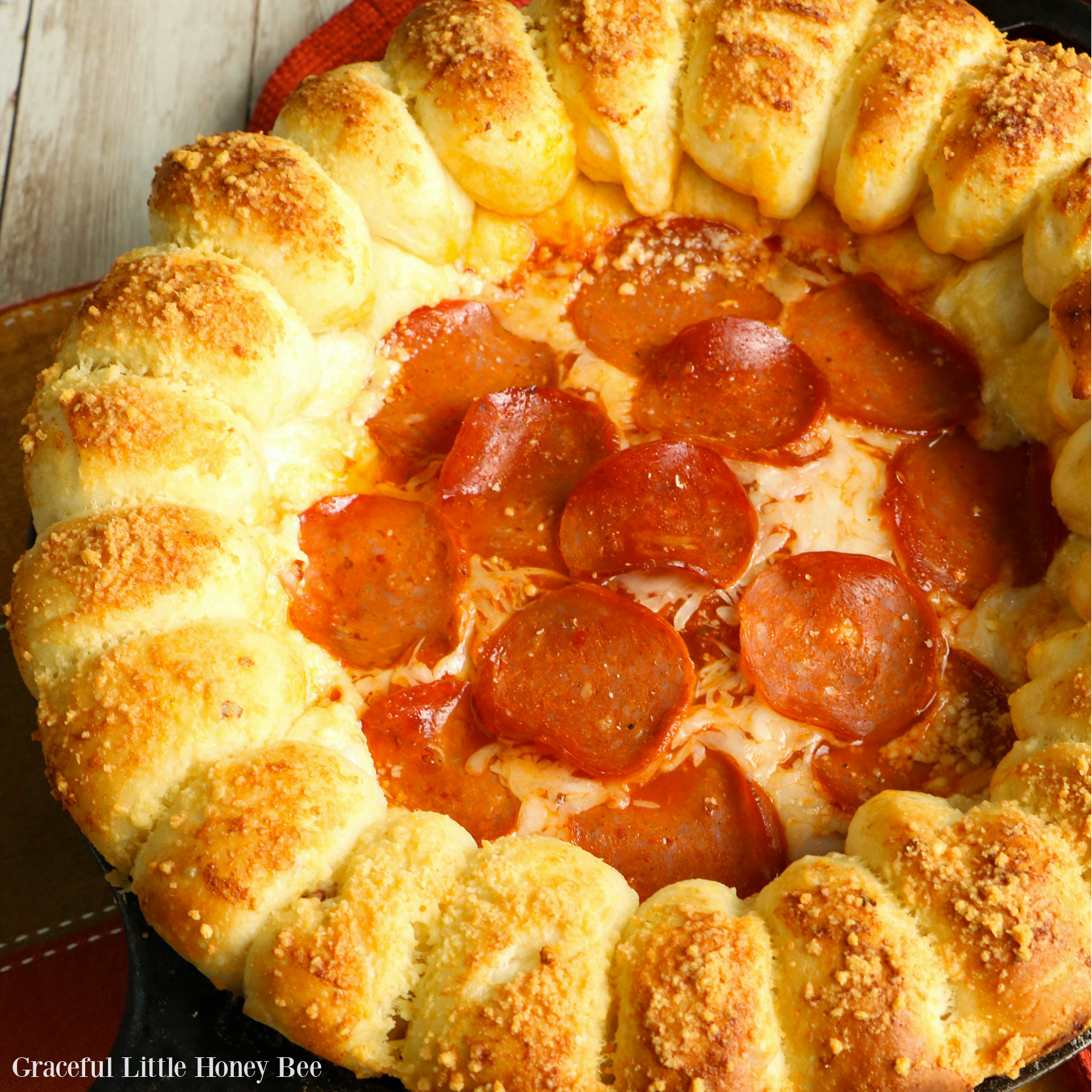 Cheesy Pizze Dip topped with pepperoni with a ring of garlic bread around it in a cast iron skillet.