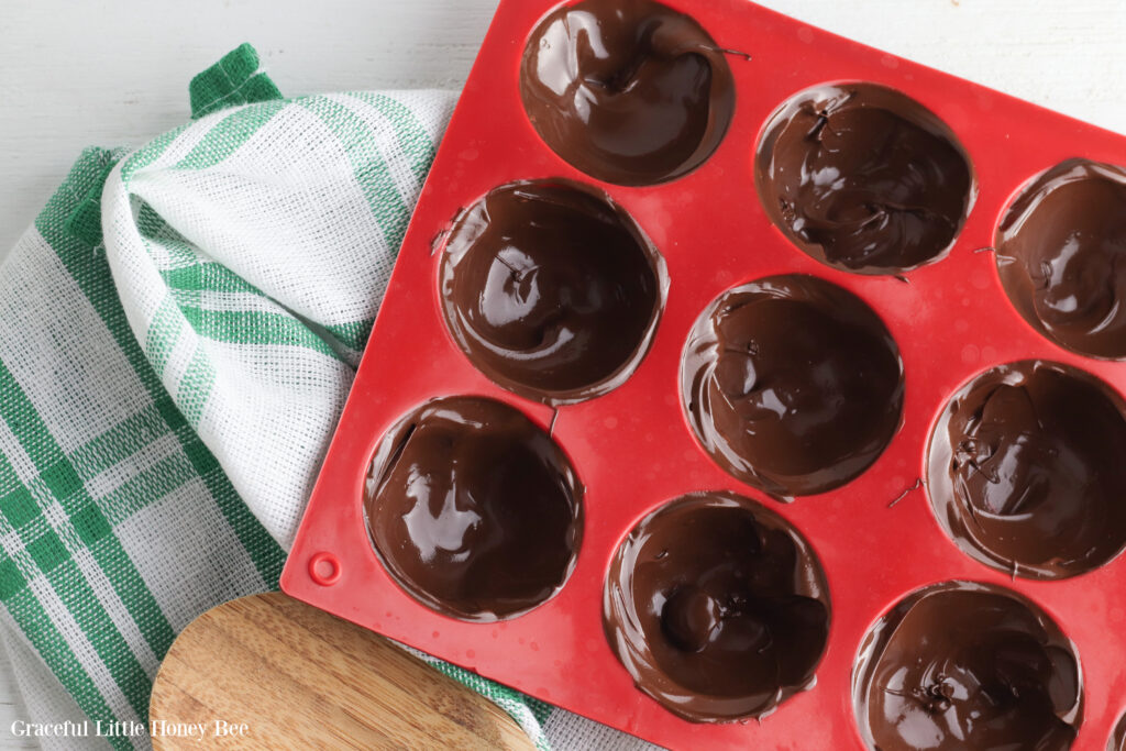 Red silicone tray filled with melted chocolate spread out in a thin layer.