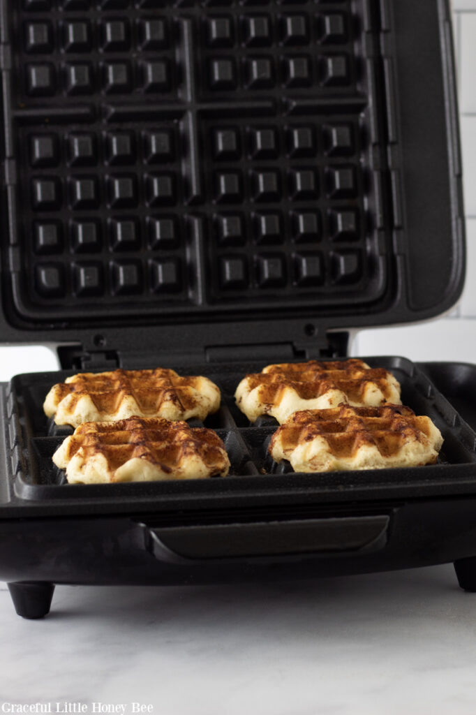 Crispy cinnamon roll waffles in the waffle iron.