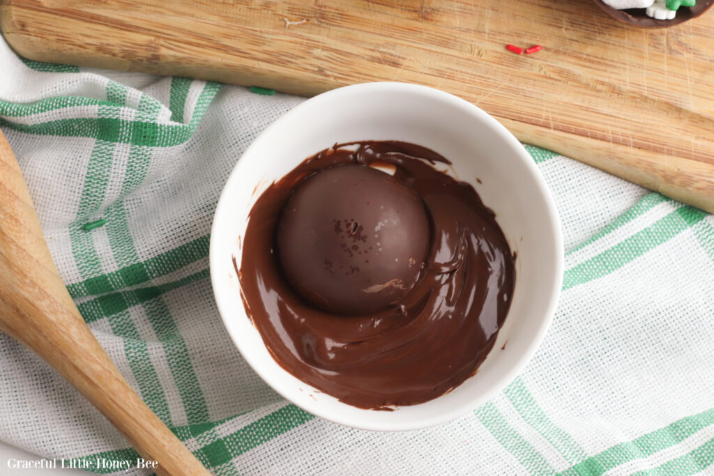 Half of hot chocolate bombs dipped in melted chocolate for sealing.