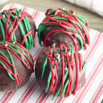 Four hot chocolate bombs sitting on a red and white striped plate.