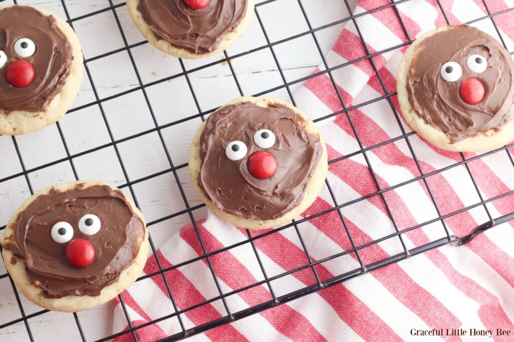 Sugar cookies with chocolate frosting, candy eyes and nose sitting on a wire cooling rack.
