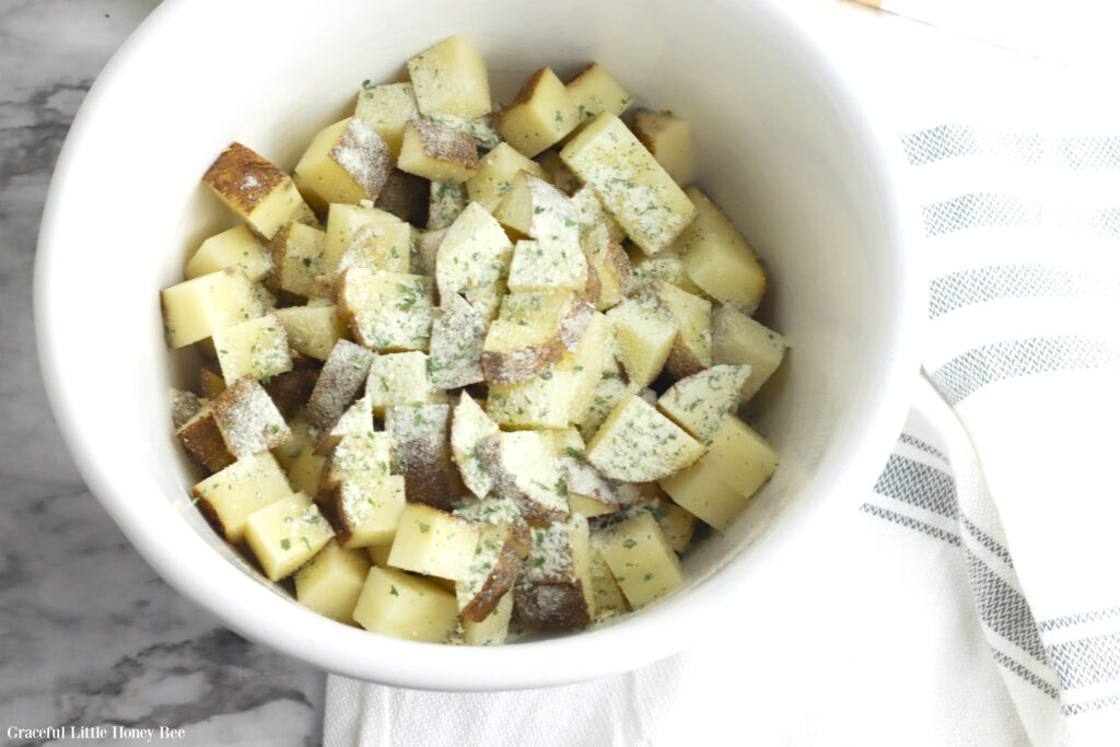 Diced potatoes in a white bowl with ranch seasoning on top.