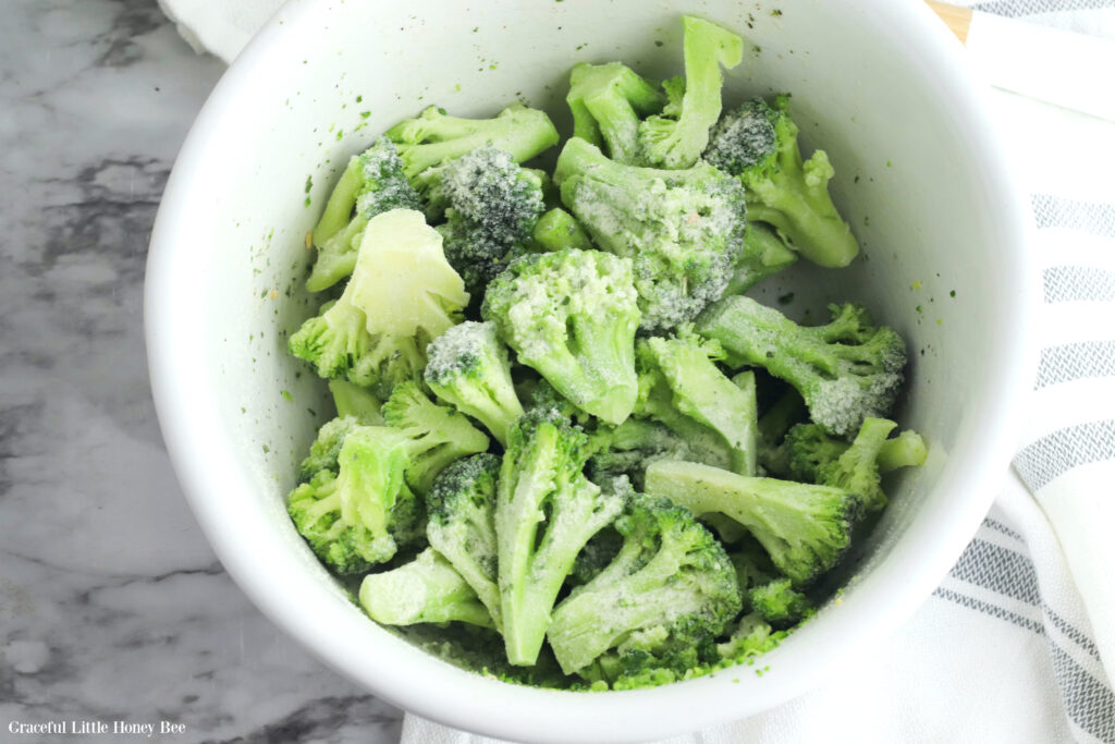 Broccoli florets in a bowl with seasoning.