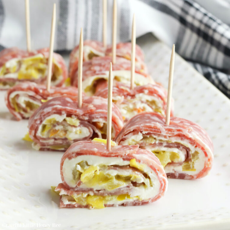 Salami Roll-Ups sitting on a white plate with a toothpick in each one.