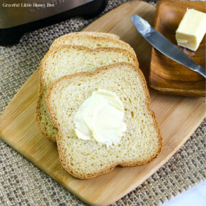 Three slices of white bread with a slab of butter sitting on a cutting board.