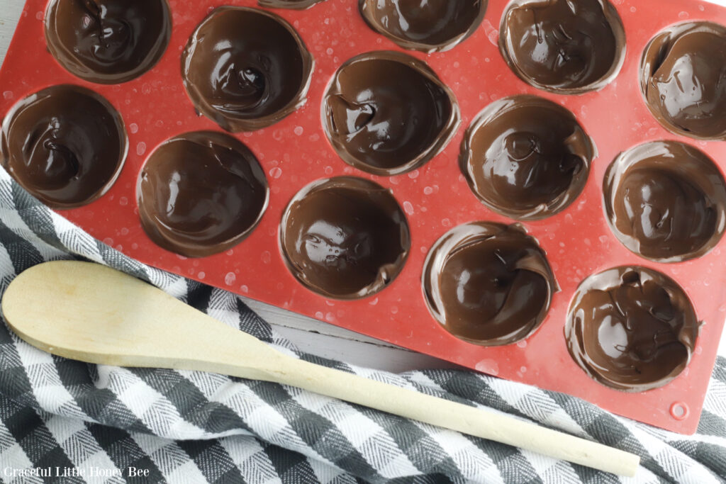 Melted chocolate in a red silicone dome mold.