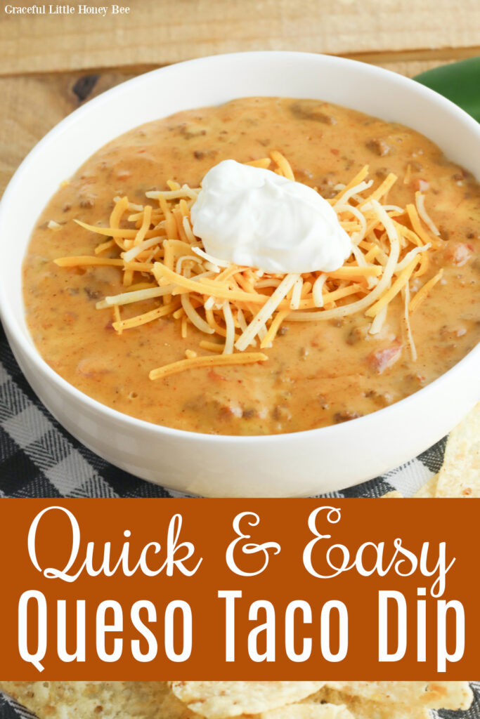 Queso Taco Dip in a white bowl topped with shredded cheese and sour cream.